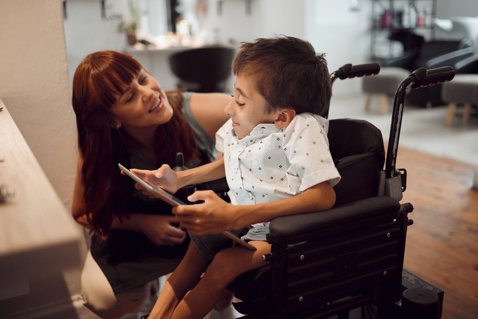 woman-child-disability-tablet-wheelchair-friendly-inclusivity-special-needs-support-cerebral-palsy-handicap-kid-screen-time-games-disabled-hairdresser-salon cantrust auto repair